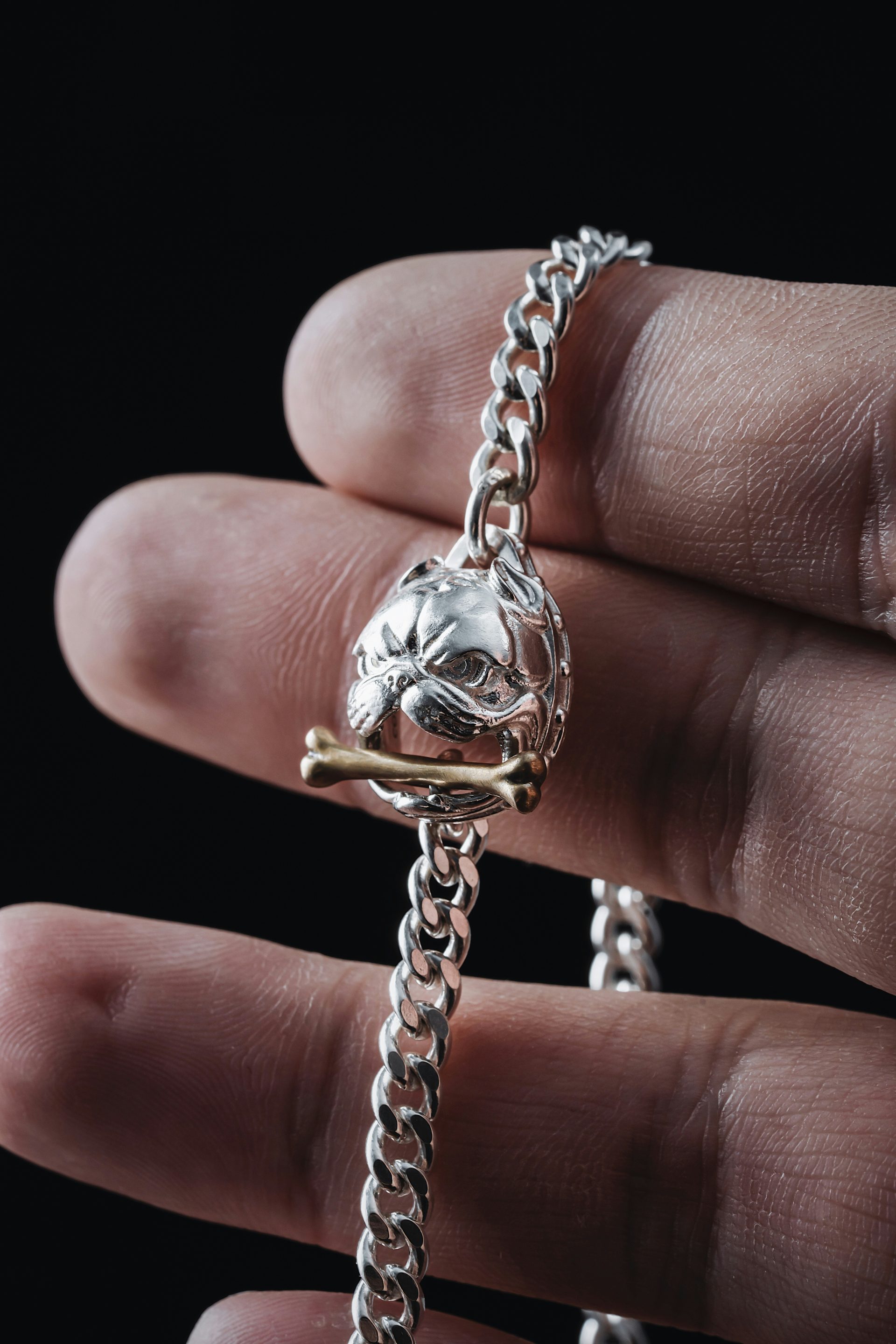 a person holding a silver bracelet with a dog head on it