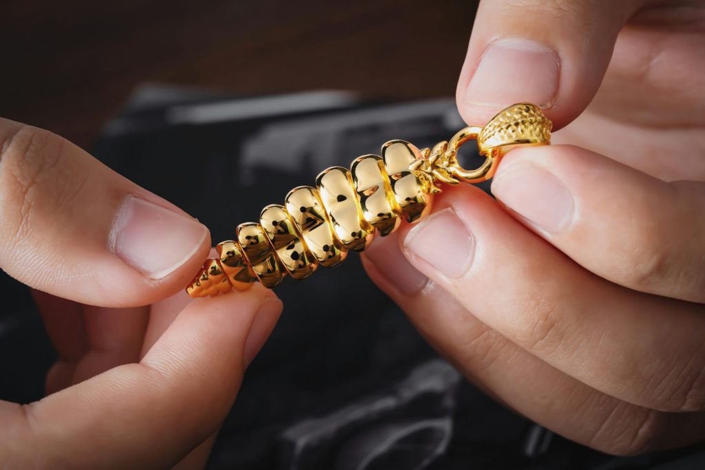 a person is holding a gold chain with a clasp on it